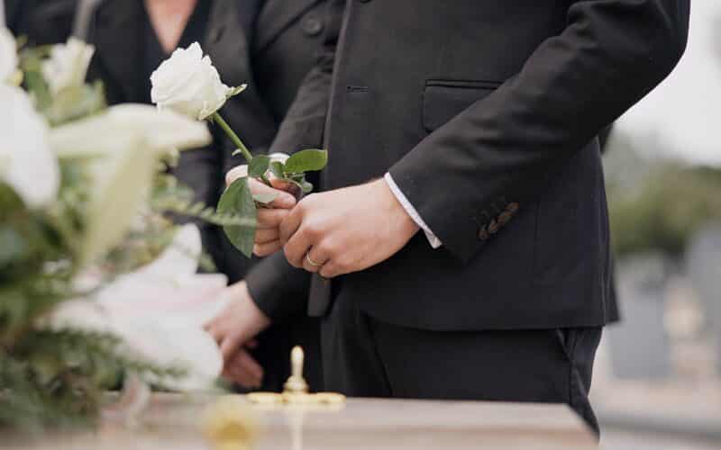 Hand,,Rose,And,A,Person,At,A,Funeral,In,A